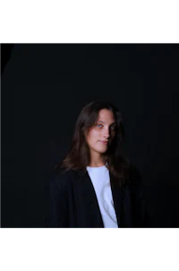 a woman in a black blazer and white shirt posing for a photo