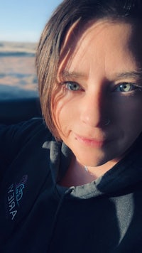 a woman in a black hoodie sitting in a car