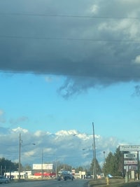 a cloudy sky over a street with cars on it