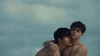 two young men hugging each other on the beach