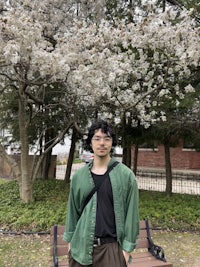 a man in a green shirt standing in front of a cherry tree