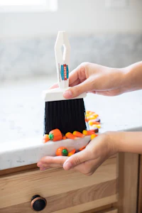 a hand holding a broom with candy canes on it