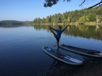 a woman standing on a paddle board on a lake