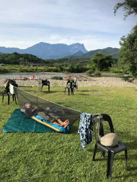a group of people laying on the grass next to a river