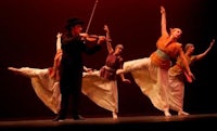 a group of dancers on stage with a violin