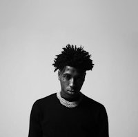 a black and white photo of a man with dreadlocks
