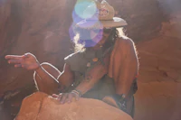 a man in a hat sitting on top of a rock