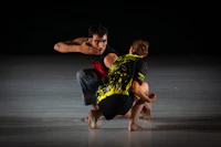 two dancers crouching on a dark stage
