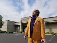 a man in a yellow suit standing in a parking lot