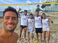 a group of men posing for a photo on the beach