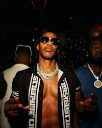 a man in a black shirt and sunglasses standing in a nightclub