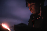 a man with dreadlocks holding a fire in front of him