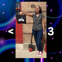 a woman holding a black bag in front of a brick wall