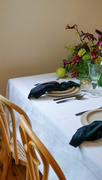 a white table setting with black chairs and a vase of flowers