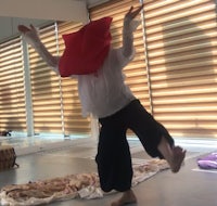 a man in a white shirt is dancing with a red bag