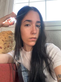 a girl with long black hair is sitting on a couch