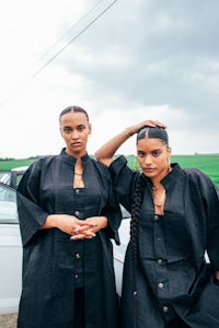 two black women standing next to a white car