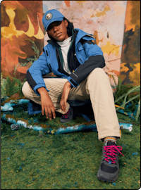 a young man in a blue jacket sitting on grass