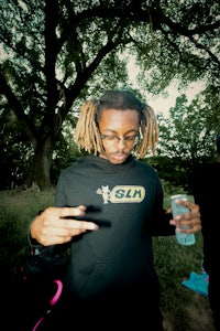 a man with dreadlocks holding a drink