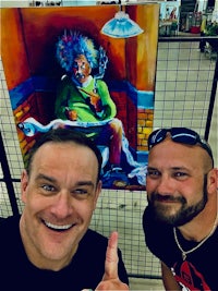 two men posing for a picture in front of a painting