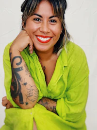a smiling woman in a green shirt with tattoos