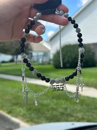 a person holding a black and silver beaded bracelet