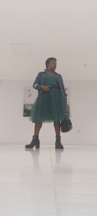 a woman in a green tulle dress standing on a white floor