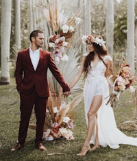 a bride and groom holding hands in front of a palm tree