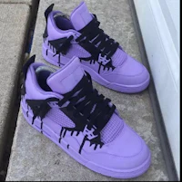 a pair of purple air jordan 4's with black dripping paint