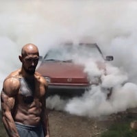 a man standing in front of a car with smoke coming out of it