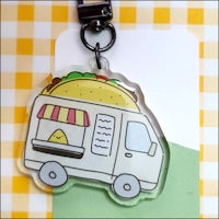 An acrylic keychain with a cartoon taco truck
