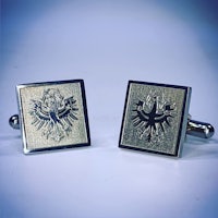 a pair of silver cufflinks with an eagle on them