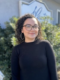 a woman wearing glasses is standing in front of a building