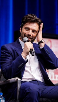 a man in a blue suit is holding a microphone