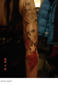 a woman has a tattoo of a skull and roses on her arm