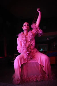 a woman in a pink dress is sitting on a chair