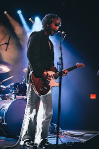 a man playing guitar on stage in front of a microphone