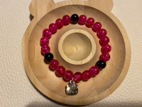 a pink and black beaded bracelet with a teddy bear charm