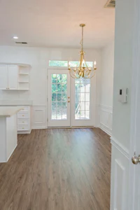 a white kitchen with hardwood floors and a chandelier