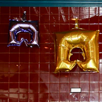 two gold foil balloons hanging on a wall
