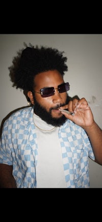 a man with a beard and sunglasses smoking a cigarette
