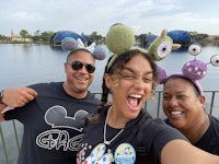 three people posing for a photo in front of a lake