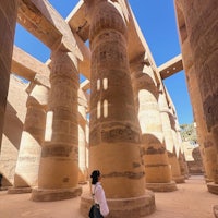 a woman is standing in front of columns in an egyptian temple