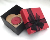 a wooden heart shaped candle in a red box