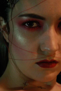 a woman with red makeup and wires on her face