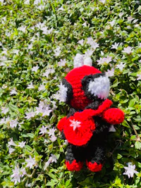 a spider - man stuffed animal sitting in a field of flowers