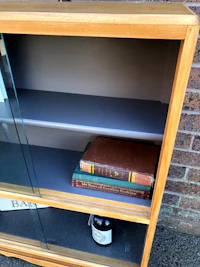 a wooden bookcase with glass doors and books on it