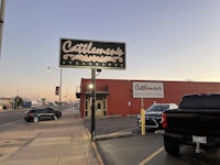a black car parked in front of a building with a sign that says catlin's