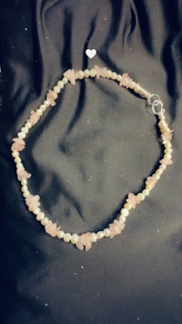 a necklace with pink and white beads on a black background