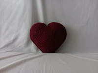 a heart shaped crocheted pillow on a bed